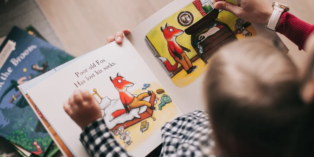 Child reading an illustrated storybook with an adult.