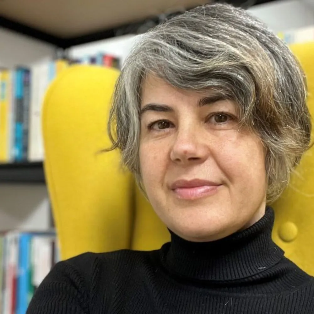 Person with short grey hair seated in a bright yellow chair.