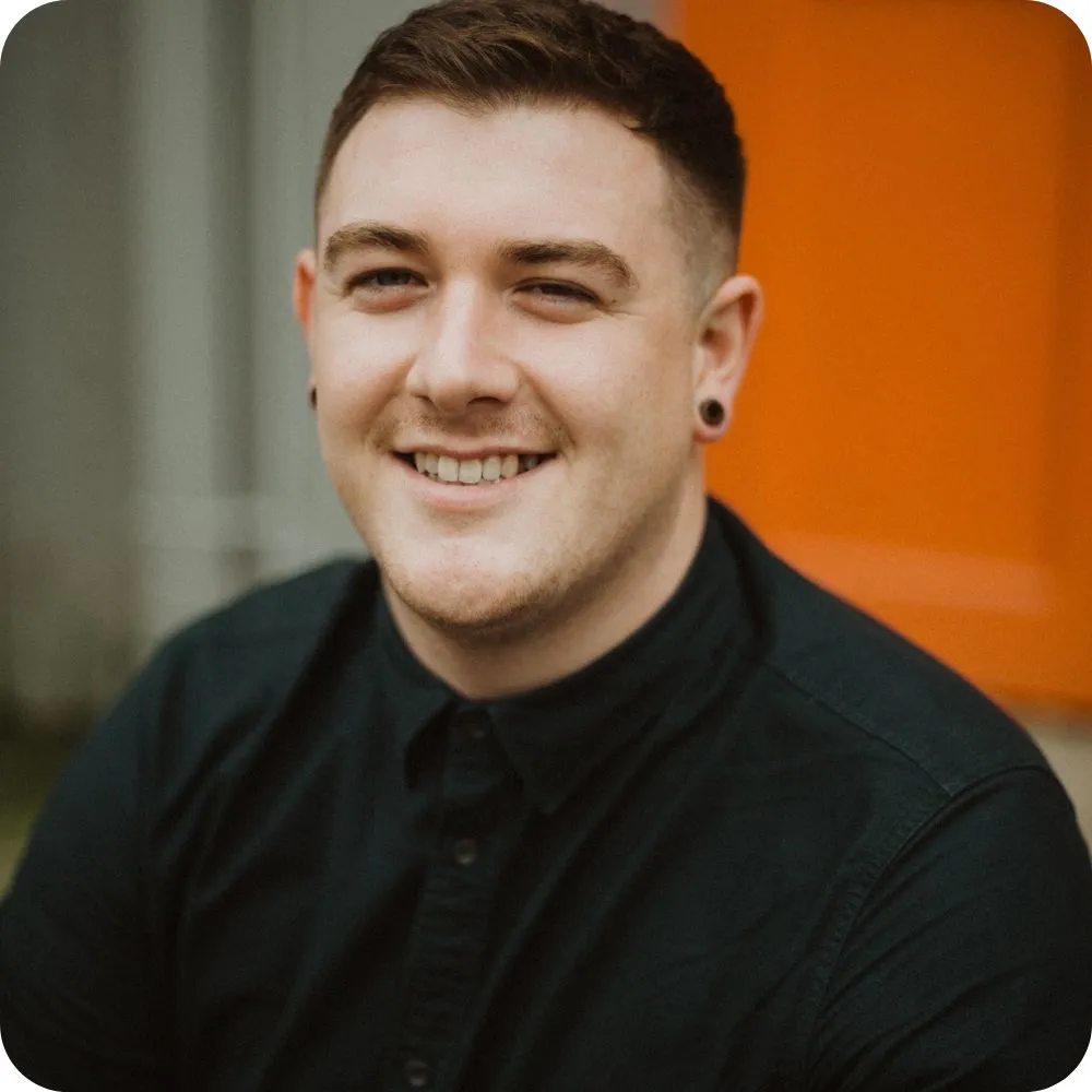 Smiling person with short hair wearing a black shirt.